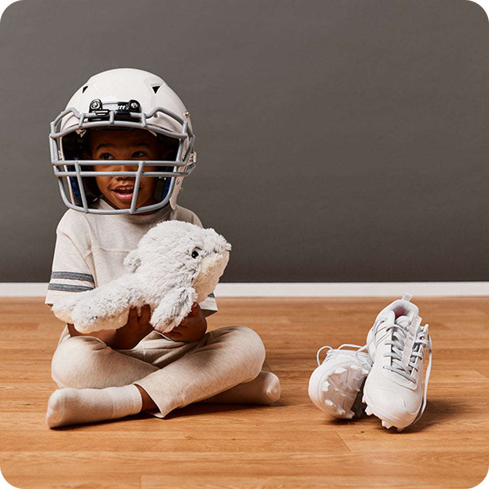 Image 102: boy in football outfit holding dolphins stuffed animal