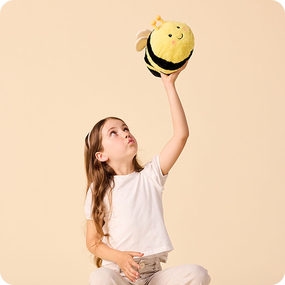 Image 105: girl holding up a bee stuffed animal warmies