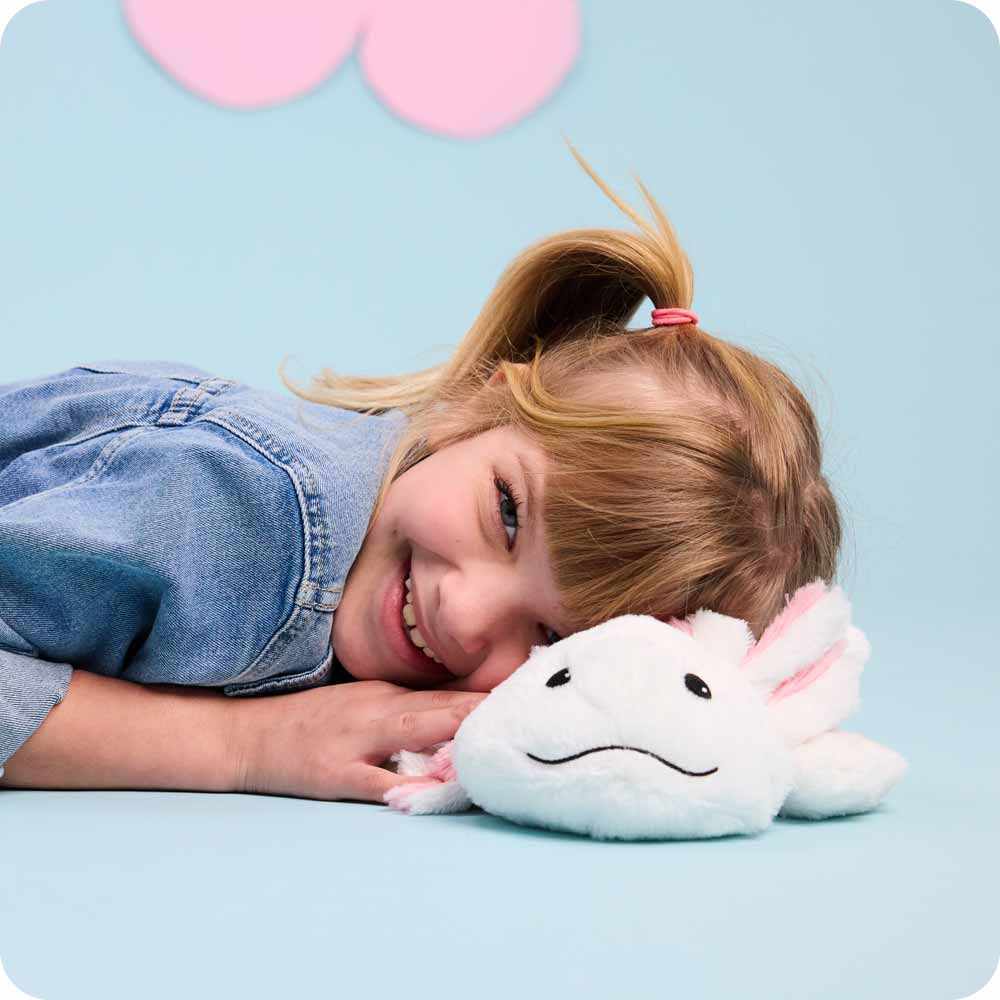 Image 102: Little girl in a jean jacket laying her head on a Axolotl Warmies