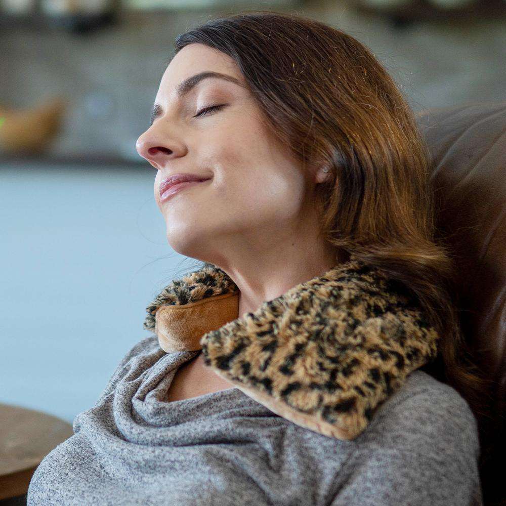 Image 89: Woman relaxing with Cozy Soft Heatable Leopard Warmies Neck Wrap.