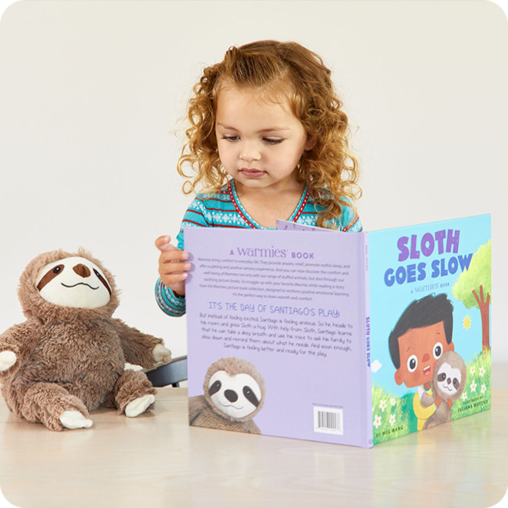 Image 92: toddler reading warmies Sloth Goes Slow book with sloth stuffed animal