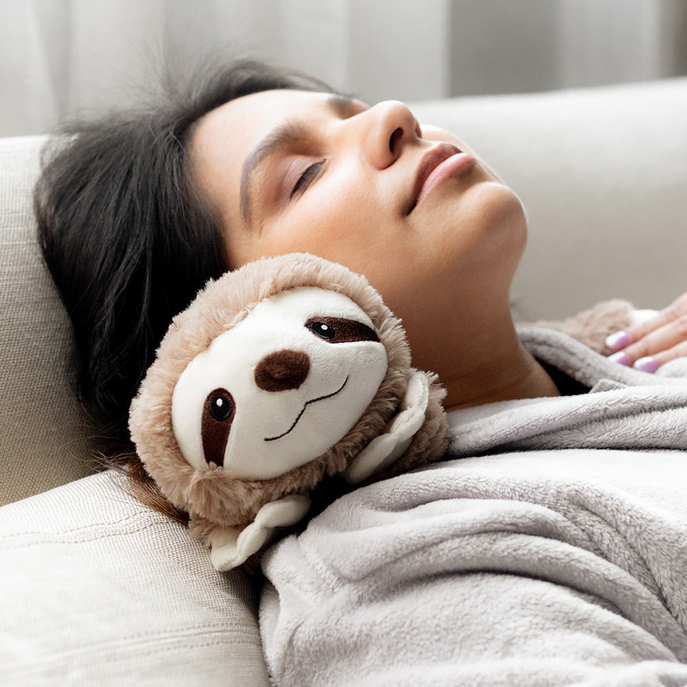 Image 95: Woman sleeping and relaxing while wearing Sloth Wrap Stuffed Animal Warmies