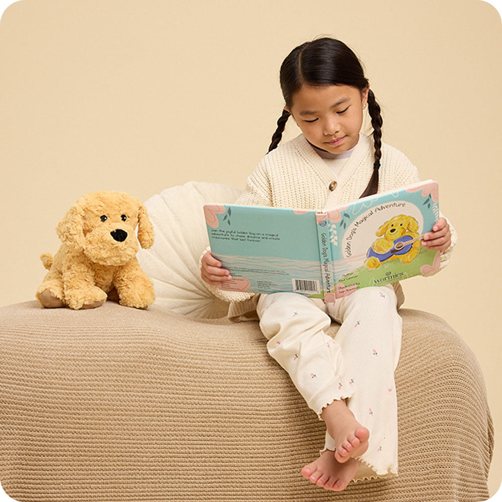 Image 89: girl reading Golden Dog's Magical Adventure warmies book with golden dog stuffed animal at her side