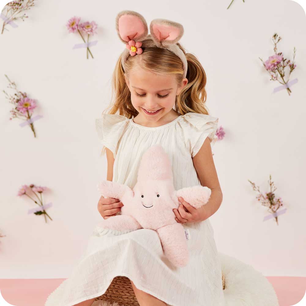 Image 98: Child smiling and holding Cute Weighted Lavender Scented Starfish Stuffed Animal Heating Pad Warmies