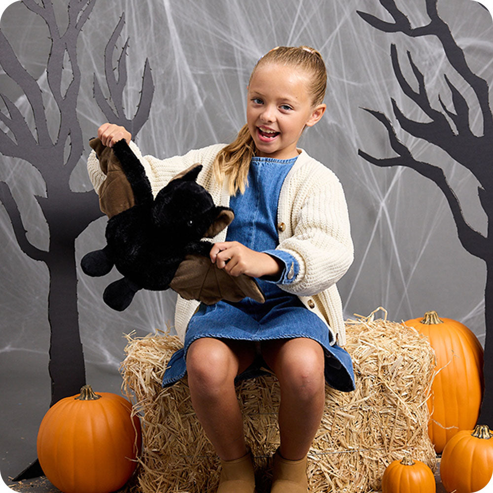 Image 100: girl holding bat stuffed animal warmies in halloween setting