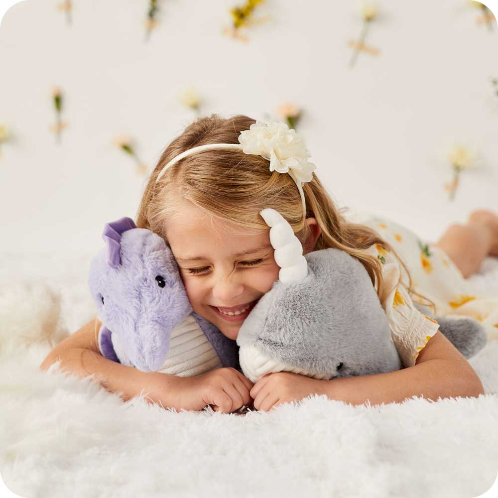 Image 97: Child laying down and cuddling a Soft Warm Weighted Seahorse Plush Warmies