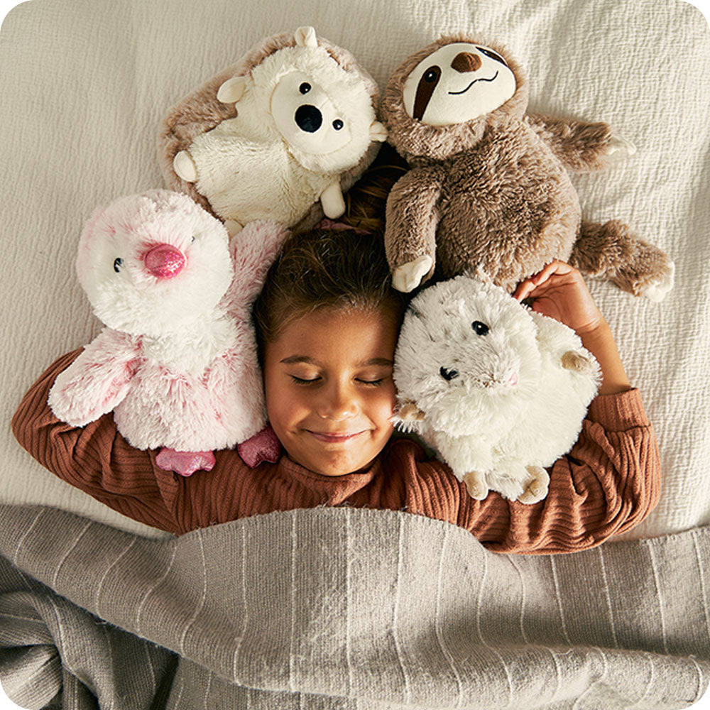Image 95: girl sleeping with 4 warmies stuffed animals hedgehog