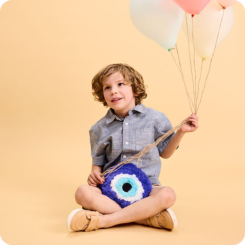 Image 99: boy holding evil eye stuffed animal warmies