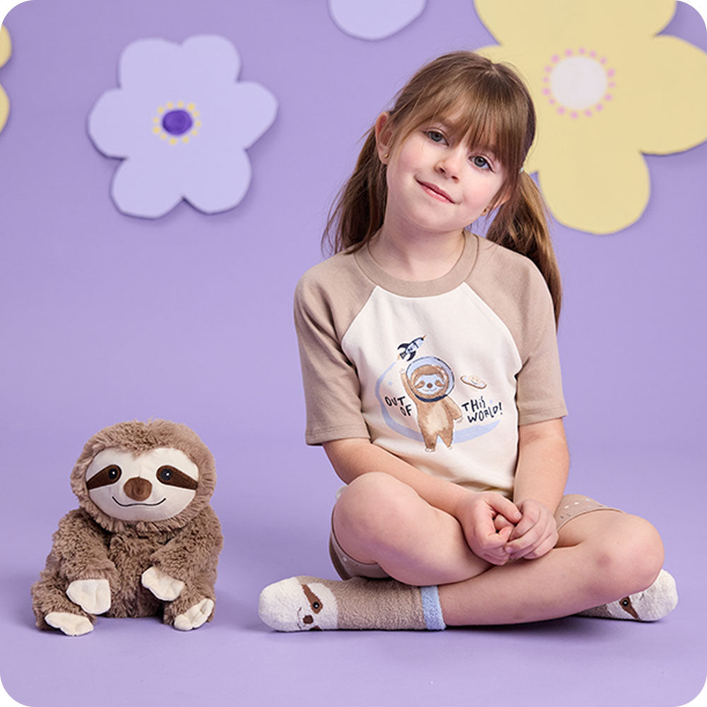 Image 104: sloth stuffed animal and girl wearing sloth socks and pajamas