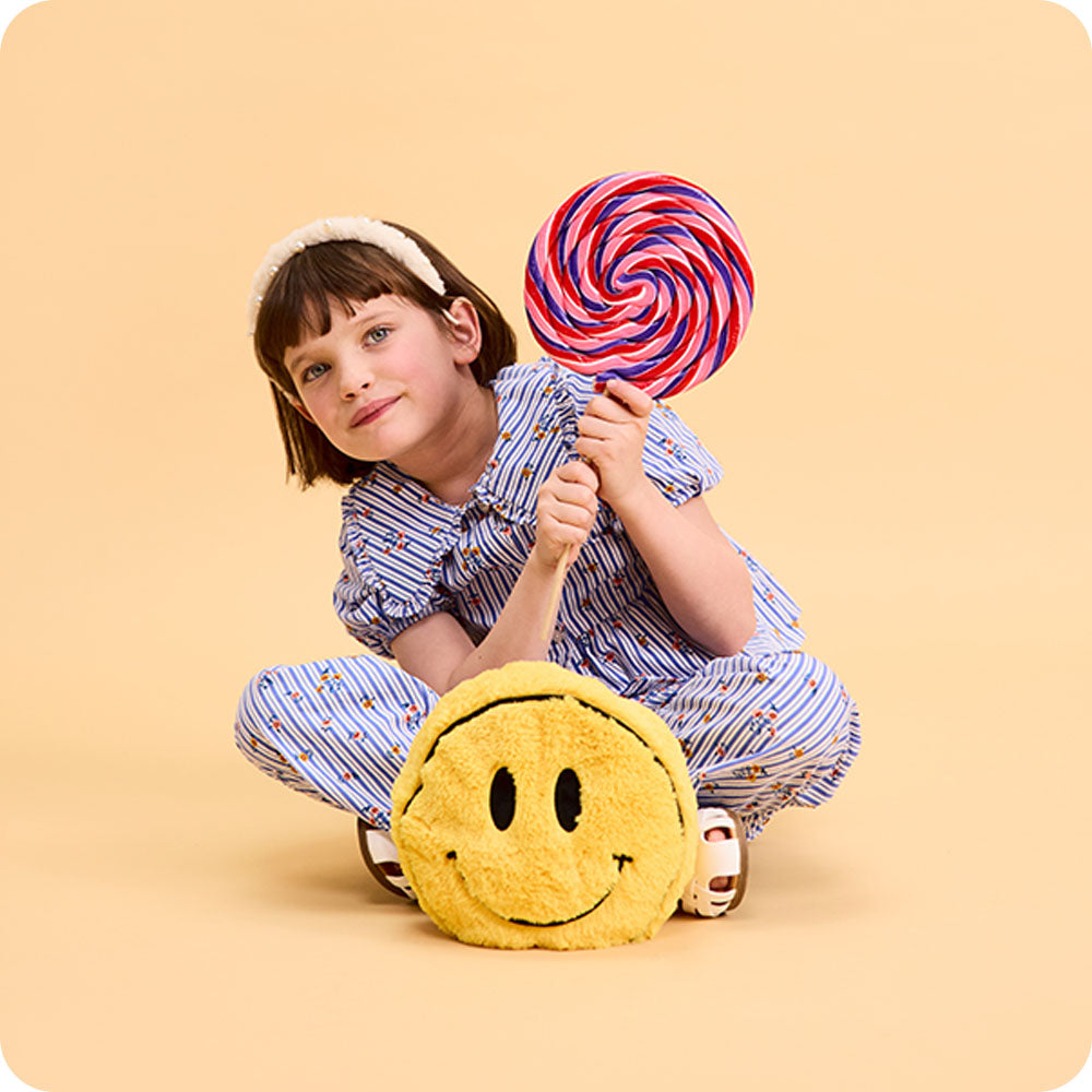Image 104: girl holding lollipop with smiley face stuffed animal warmies