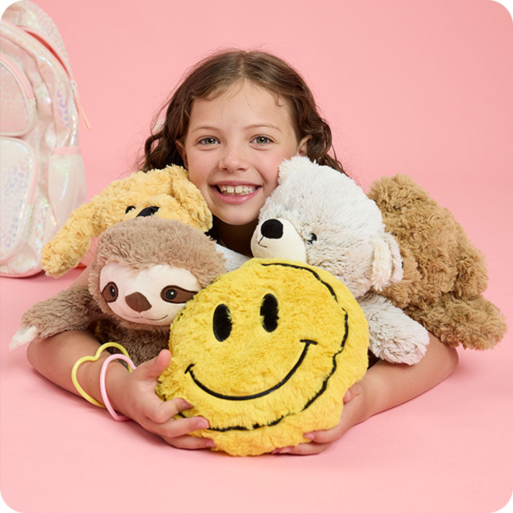 Image 105: girl hugging pile of stuffed animals with smiley face stuffed animal warmies