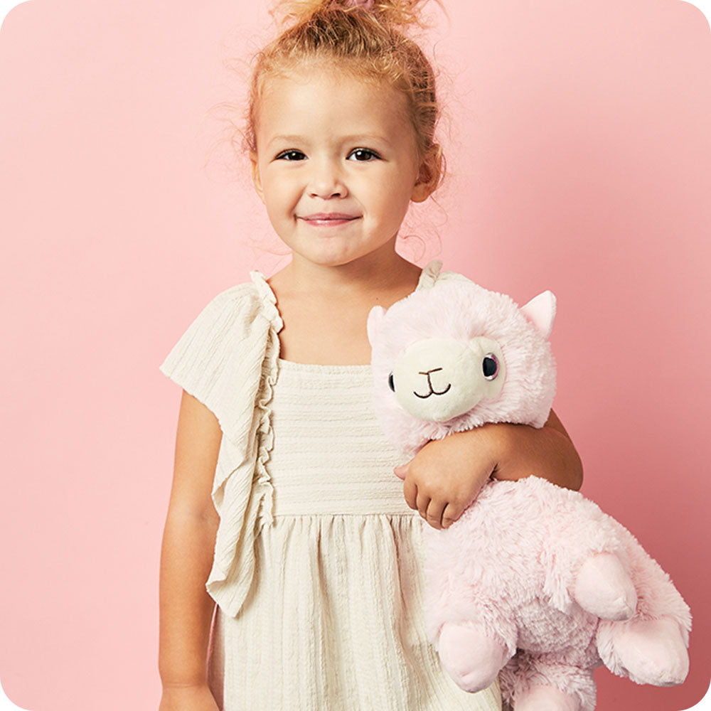 Image 99: girl holding a warmies pink llama stuffed animal
