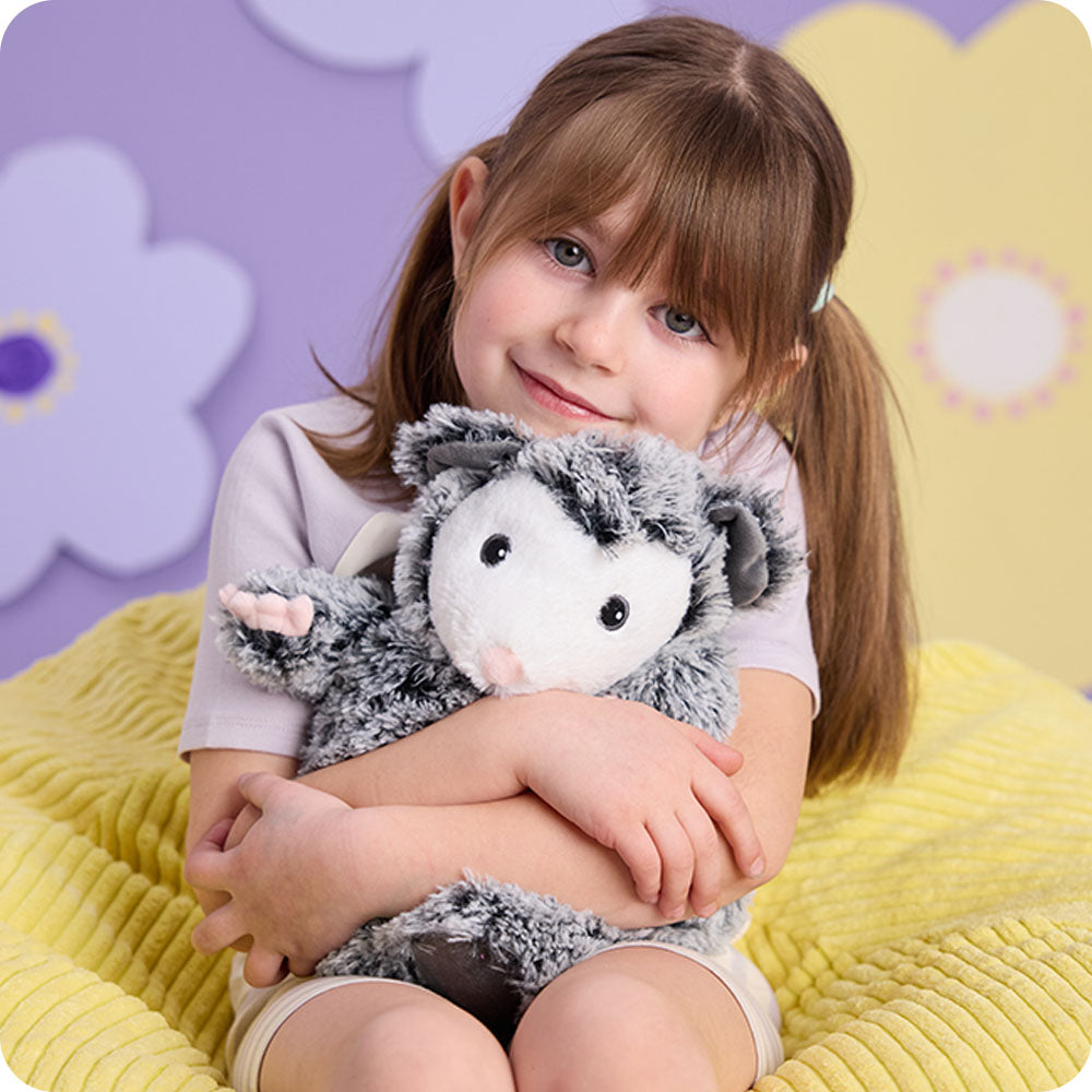 Image 103: girl hugging opossum stuffed animal warmies